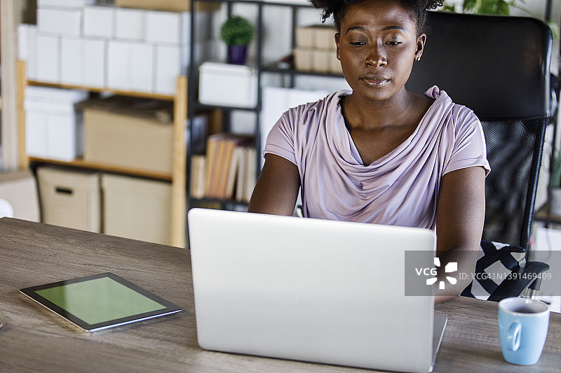 勤奋的商业女性使用笔记本电脑和数字平板电脑的色度键在她的办公桌图片素材