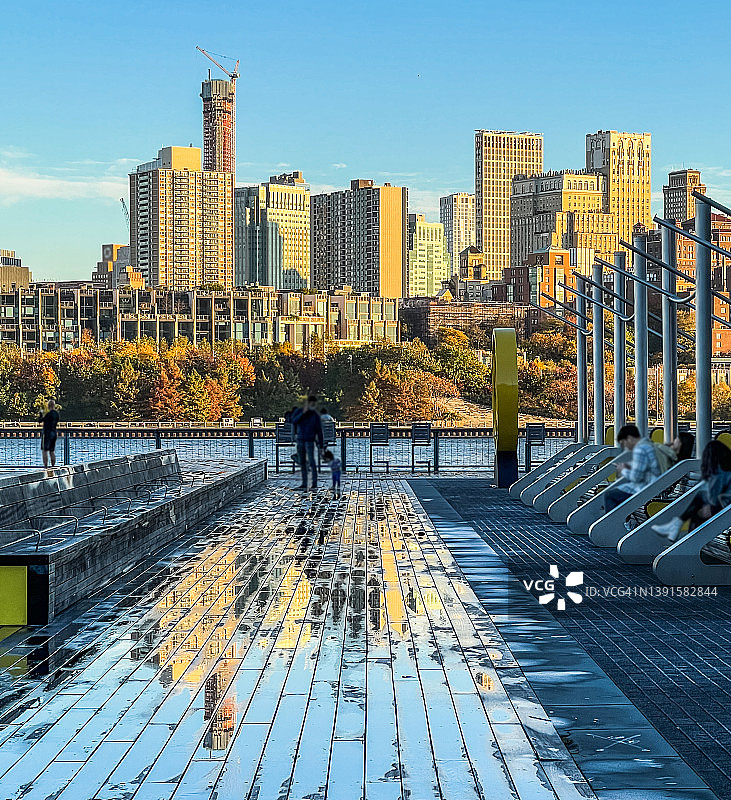 秋天的布鲁克林天际线景观反射在纽约潮湿的木板路上图片素材