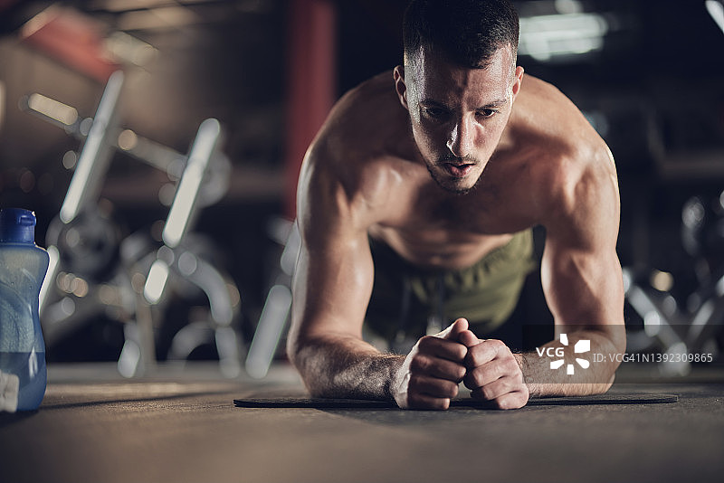 肌肉发达的男子在健身房做平板支撑锻炼耐力。图片素材