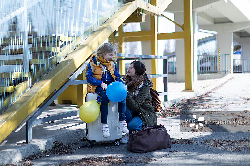 乌克兰移民的母亲和女儿带着行李在火车站等候。图片素材