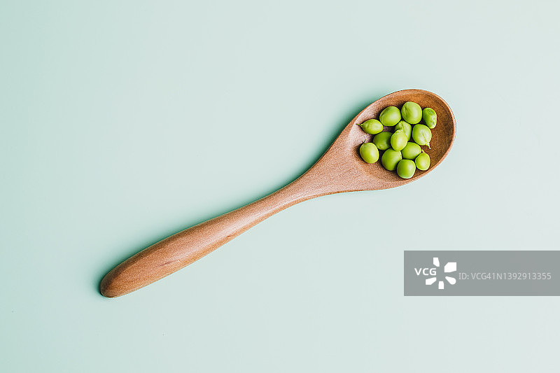 木勺上的绿色豌豆的俯视图，绿色的背景象征着健康的饮食图片素材