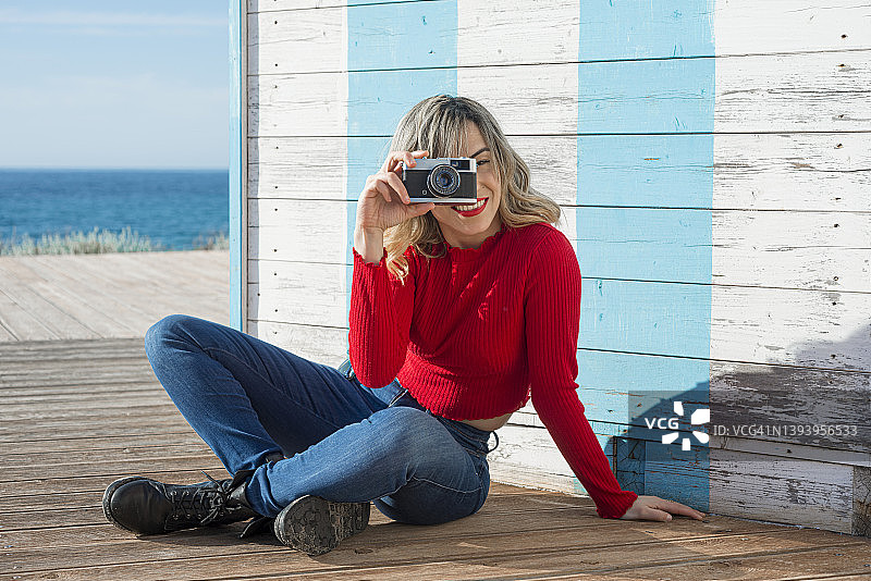 在海上坐在木地板上拍照的女人图片素材