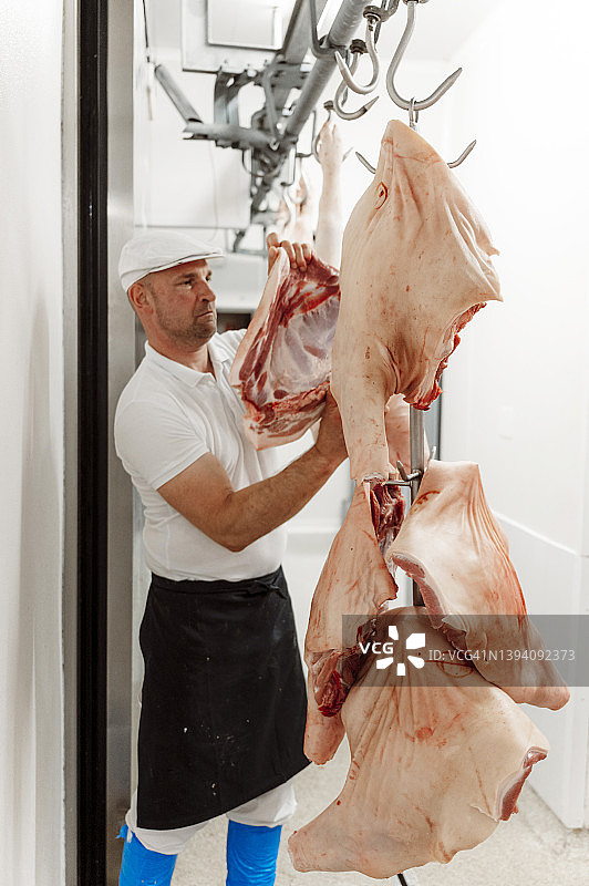 屠夫把大块的肉挂在钩子上图片素材