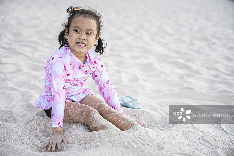 亚洲小女孩坐在沙滩上图片素材