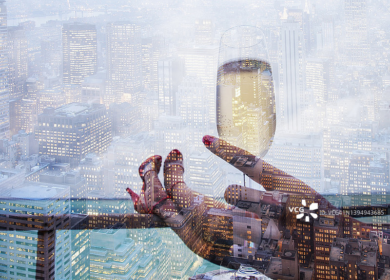 在一座城市的阳台上，一个女人拿着一杯香槟图片素材