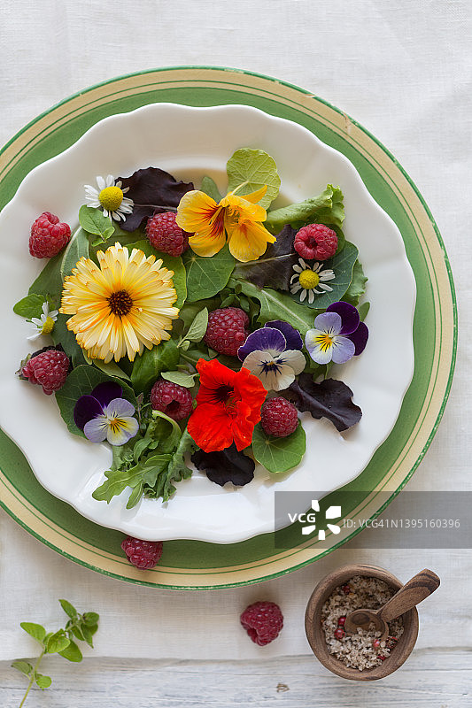 夏季沙拉，浆果和可食用的花朵在盘子上图片素材