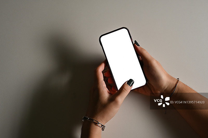 俯视图平板手持智能手机与白色背景上的白色空白屏幕，为通信和技术概念。图片素材