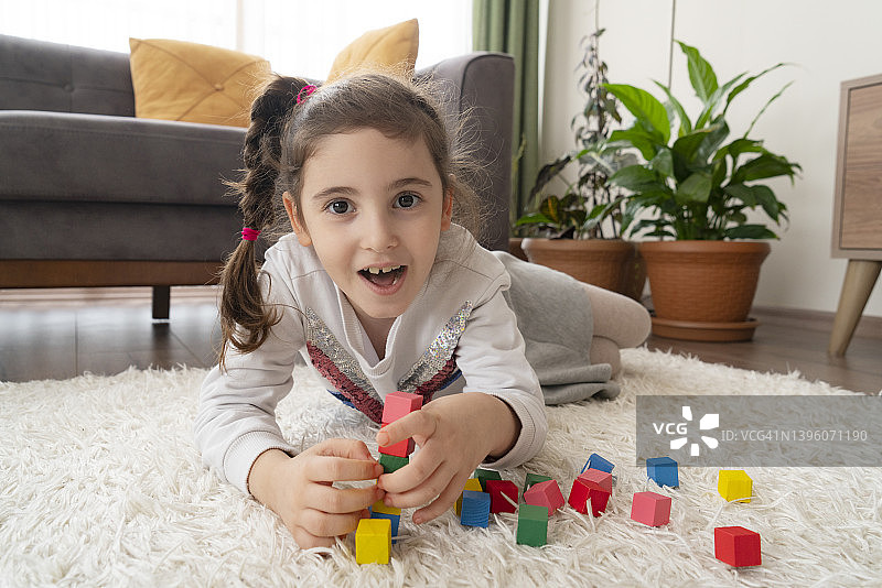 可爱的小女孩在家里玩五颜六色的积木图片素材