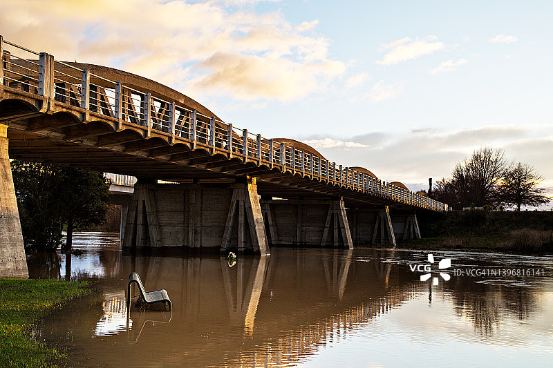 在新西兰布莱尼姆的日出金色灯光下，大雨过后淹没的漫滩和Opaoa (Opawa)桥图片素材