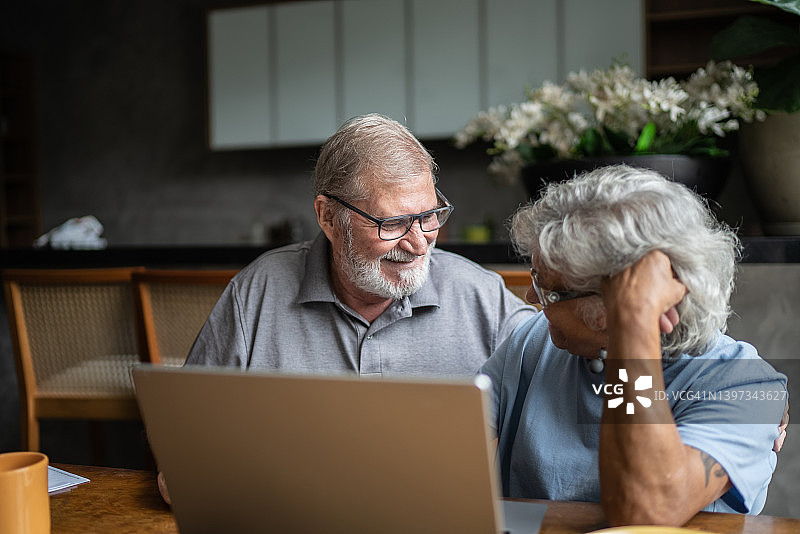 快乐的老年夫妇在家使用笔记本电脑图片素材