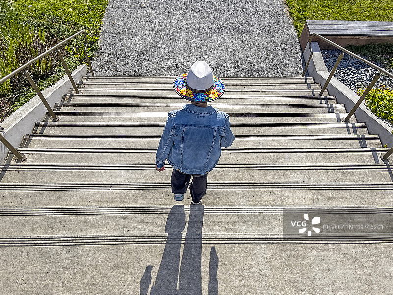一个戴着彩色帽子的女人走下室外楼梯的俯瞰视图。图片素材