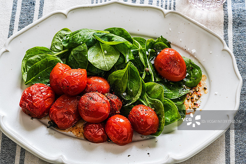 植物素食餐。沙拉配新鲜菠菜和烤樱桃番茄图片素材