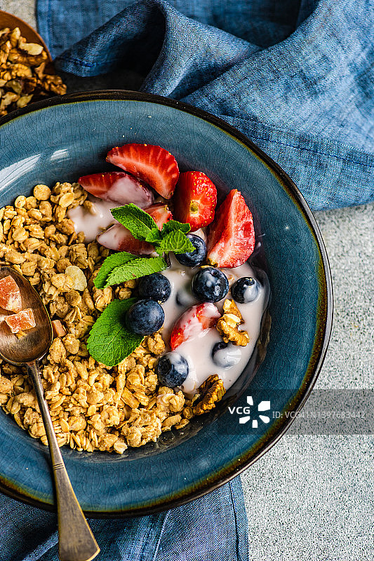 俯瞰一碗格兰诺拉麦片，蓝莓，草莓，核桃和酸奶图片素材