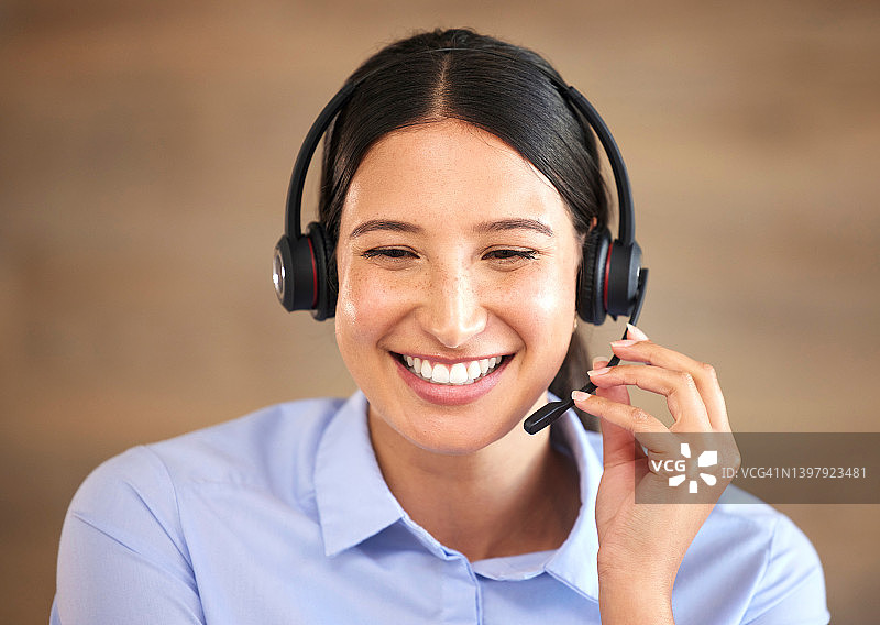 特写微笑的混合种族呼叫中心代理人说话的客户与耳机。西班牙女商人接听电话，从办公室帮助客户。客服代表头像图片素材