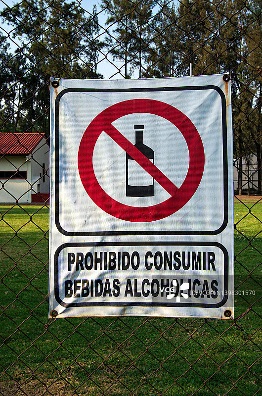 足球场周围的铁丝网上挂着西班牙语标语，上面写着“禁止饮酒alcohólicas”(禁止饮酒)图片素材