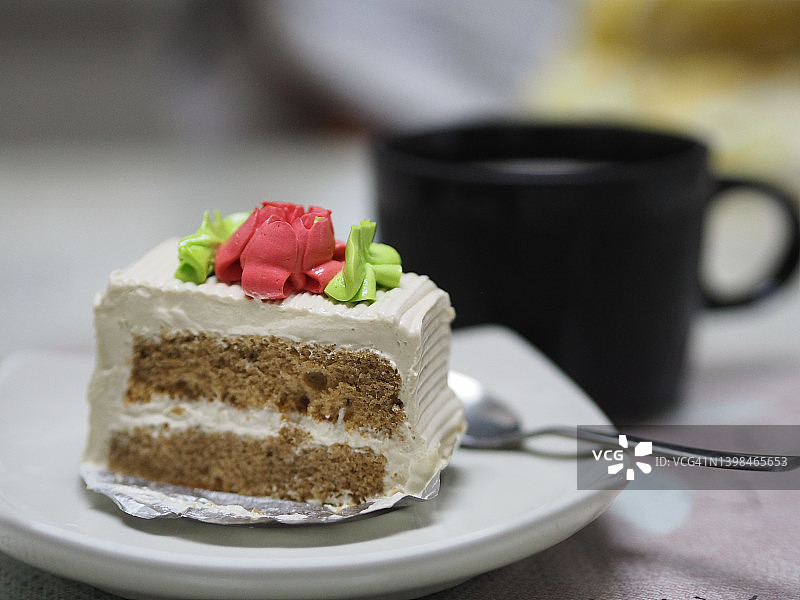 咖啡蛋糕小结节与鲜奶油在白色的盘子和热咖啡在黑色的杯子在桌子上图片素材