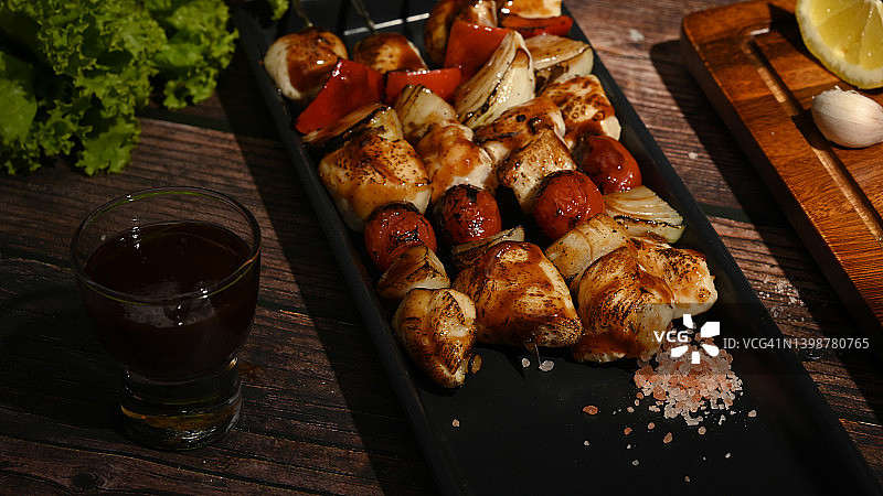 自制的鸡肉串，配樱桃番茄，甜椒和洋葱，放在木桌上。烧烤，食物，聚会的概念。图片素材