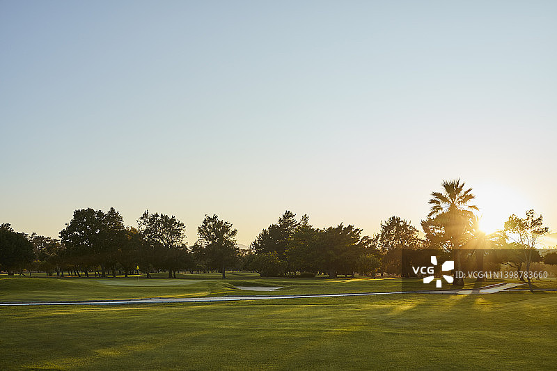 阳光明媚的日子里，高尔夫球场对着天空图片素材