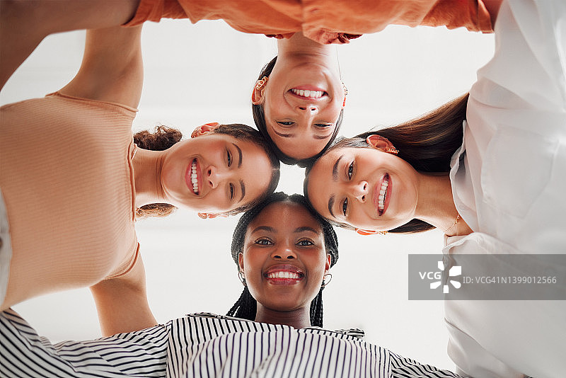 肖像快乐的商业女性在一起的头在一个办公室在工作圈。一群性格开朗的商人，他们站在一起，相互支持，玩得很开心图片素材