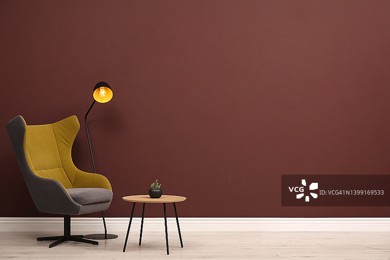时尚的扶手椅，桌子和台灯靠近棕色的墙壁，文字空间图片素材