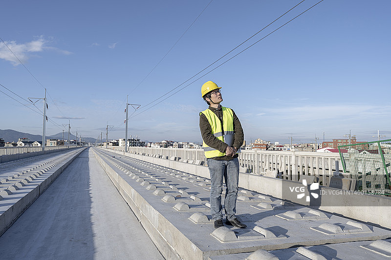 一位亚洲男性工程师在一个未完工的铁路工地上工作图片素材