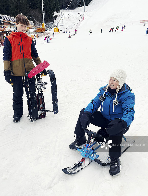 奶奶和孙子坐在雪橇上享受滑雪假期的乐趣图片素材