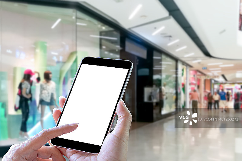 模拟女人手握和使用的智能手机与空白屏幕的购物中心图片素材
