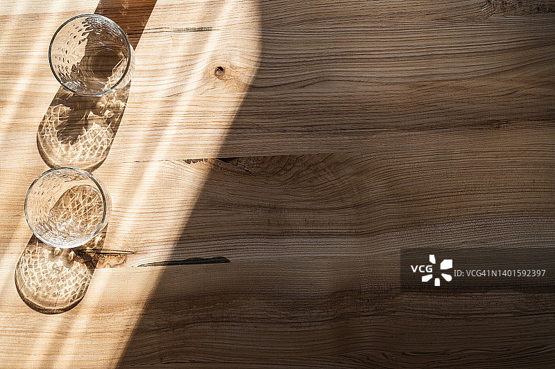 夏季健康饮料的季节。木桌上的空玻璃杯有阴影图片素材