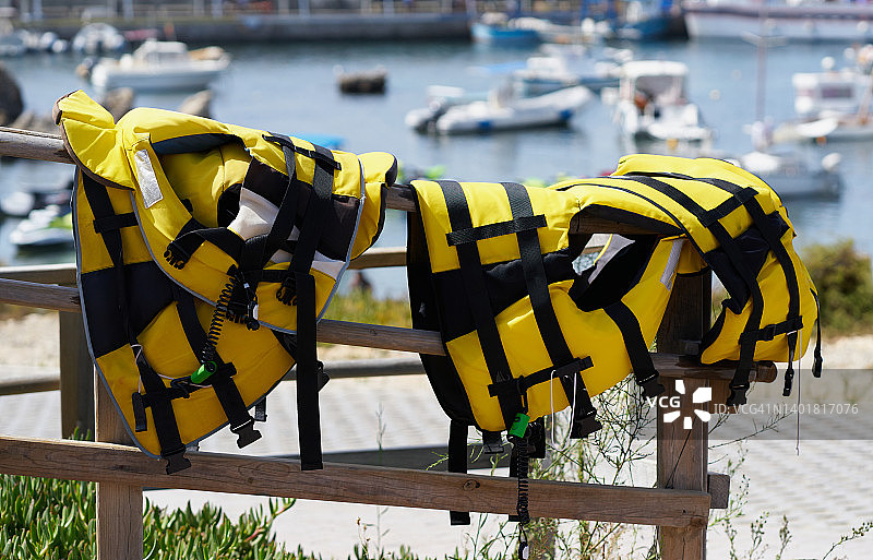 场景集中在一个阳光明媚的夏日，两件黄色救生衣躺在欧洲船坞的栏杆上。图片素材