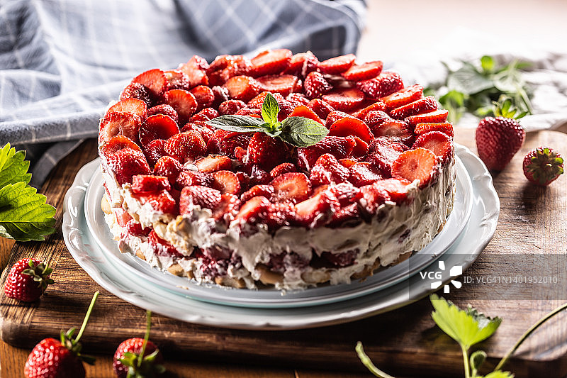 白色盘子里放着草莓奶油蛋糕和海绵蛋糕。图片素材