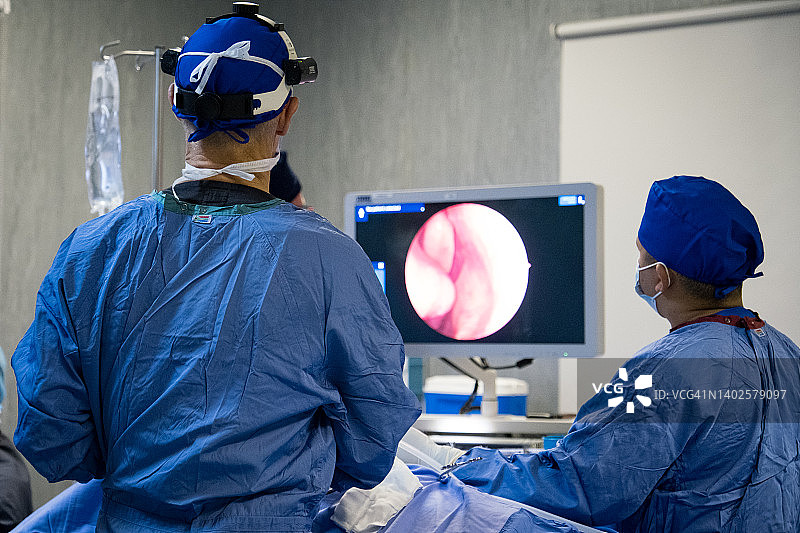 两名神经外科医生通过数字屏幕监控手术过程图片素材