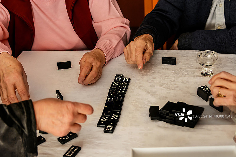 在社交会议上，年长的参与者正在玩多米诺骨牌，玩得很开心。图片素材