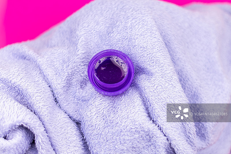 紫色洗衣液放在量杯里，放在毛巾上。图片素材