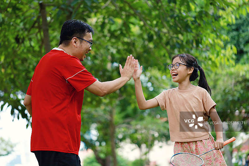 父亲和女儿在公园里击掌，打羽毛球图片素材