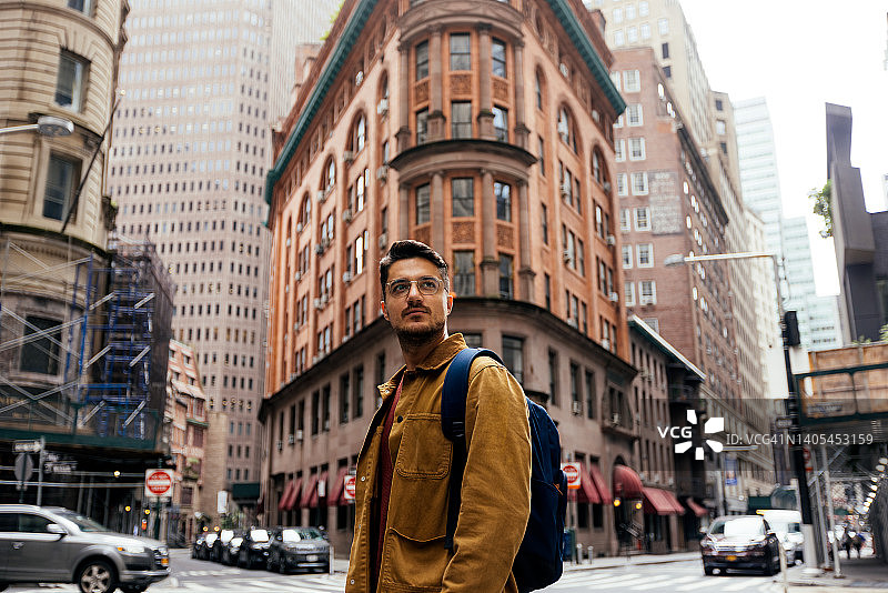 在美国纽约市的街道上，一个戴眼镜的年轻人的肖像图片素材