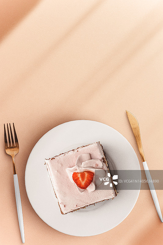 在粉红色的盘子和粉红色的表面草莓蛋糕片。俯视图图片素材