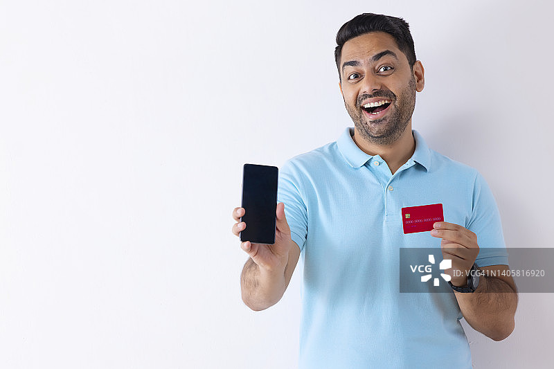 一名年轻男子在网上购物时出示了他的智能手机和信用卡图片素材