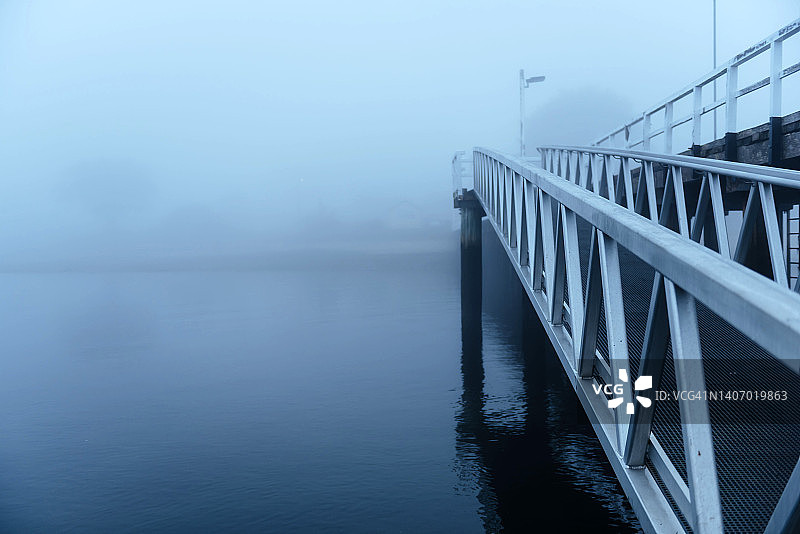 在雾蒙蒙的早晨，在宁静的碧海之上的码头图片素材