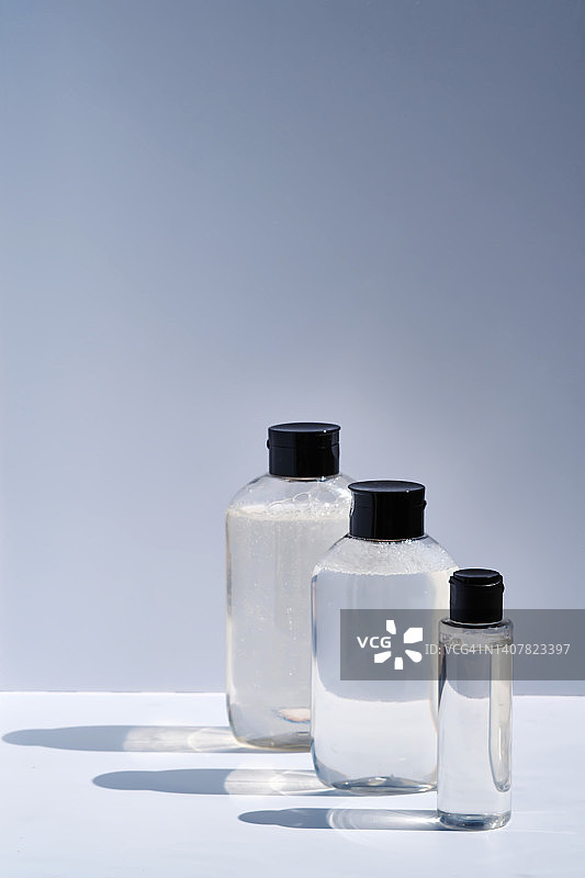 洗发水，沐浴露和胶束水放在透明的罐子里，在浅色的背景上。图片素材