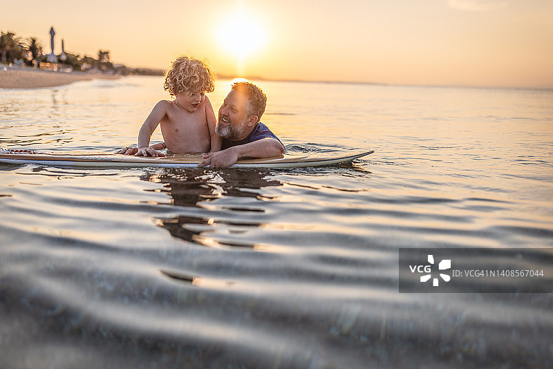 父子俩喜欢在日落时分玩冲浪板图片素材