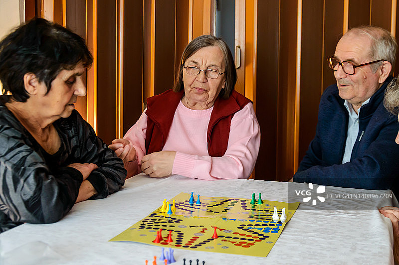 一群老年人通过玩ludo游戏参加一个社交活动。图片素材