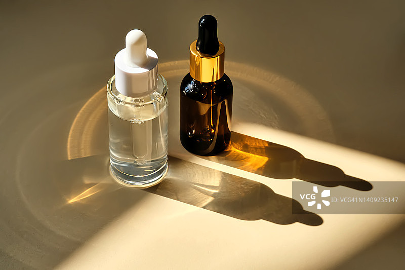 两瓶精华液在阳光和美丽的亮点。图片素材