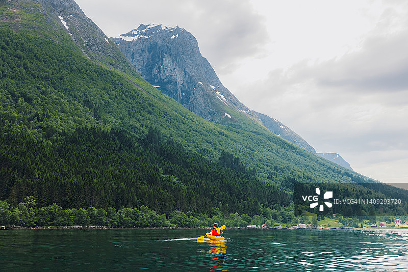 在挪威风景优美的峡湾上享受夏日皮划艇的男人的后视图图片素材