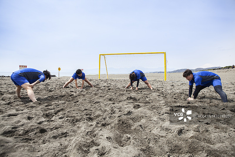 沙滩足球运动员在比赛前做伸展运动。图片素材