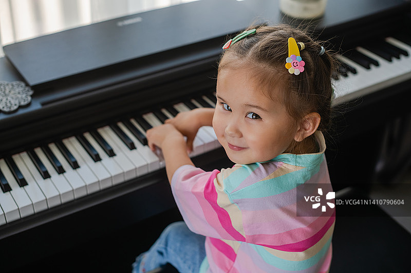亚洲小女孩弹钢琴很开心。图片素材