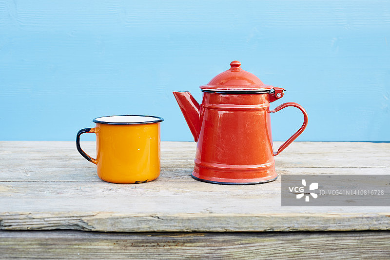 橙色珐琅杯和红色咖啡壶的静物图片素材