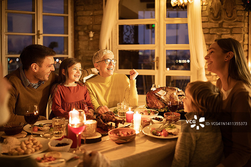感恩节晚餐时，几代人在家里谈笑风生。图片素材