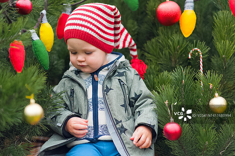 可爱的蹒跚学步的孩子抱着圣诞球在装饰的后院特写和拷贝空间。快乐的庆祝活动。快乐的童年概念……图片素材