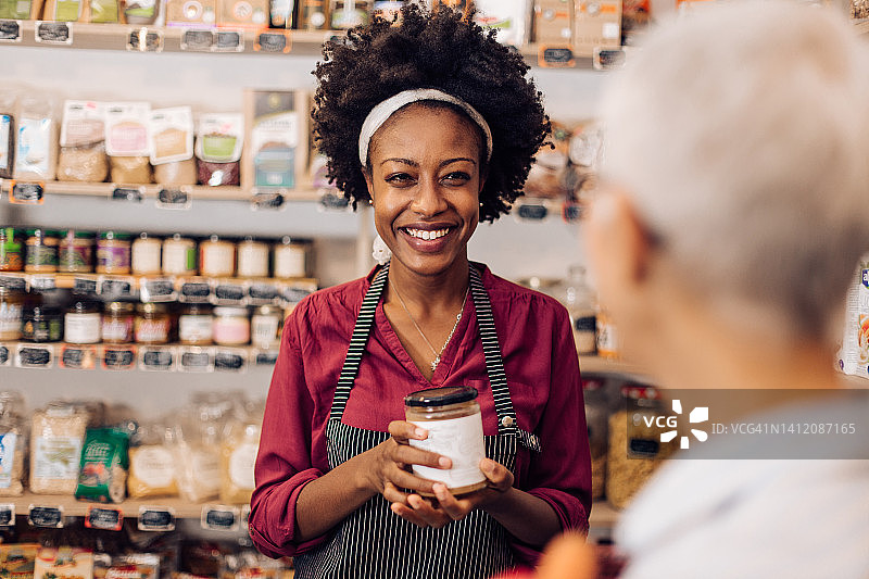 在重新开张的健康食品店，一位非洲裔女售货员正在接待一位顾客图片素材