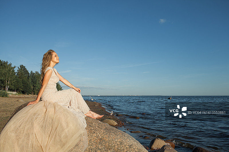 在波罗的海的海滩上，美丽的金发女子穿着完美的裙子图片素材